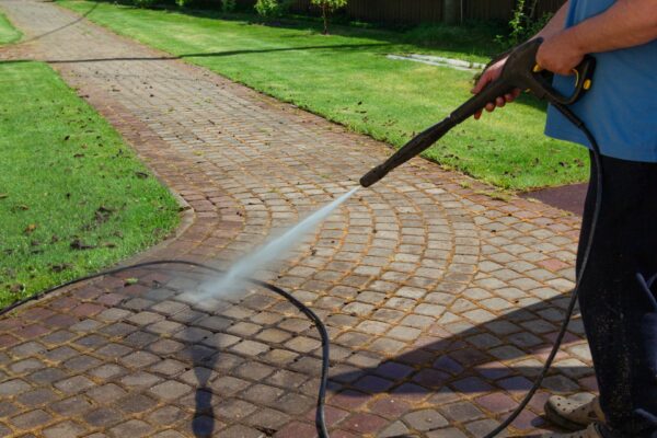 Cleaning street with high pressure power washer, washing stone garden paths